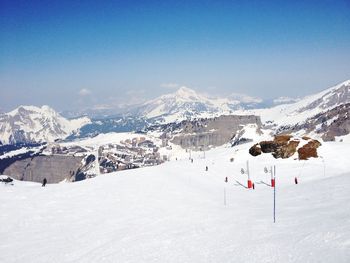 Panoramic view of people skiing on snowcapped mountain against sky