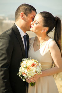 Bridegroom kissing bride while standing outdoors