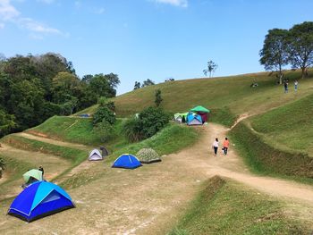 People walking on land against blue sky