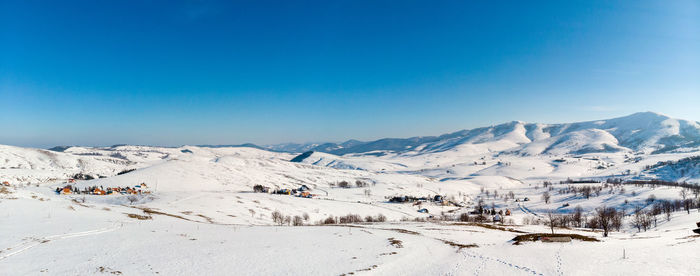 Scenic view of snowcapped mountains against clear blue sky