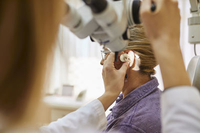 Ent physician examining ear of a senior woman