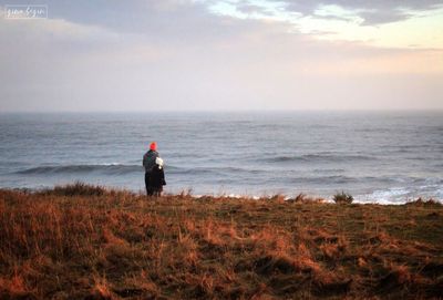 Rear view of man standing on beach against sky