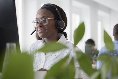 Mid adult woman using headset while sitting in office