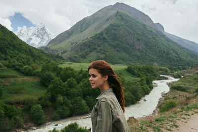 Portrait of young woman standing against mountain