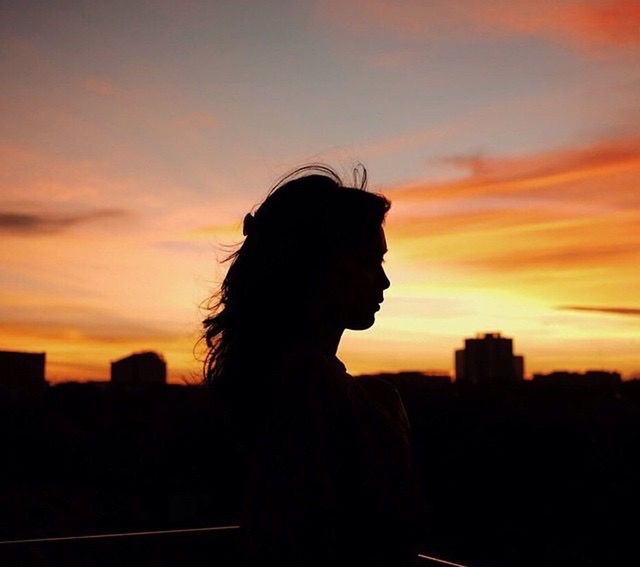 sunset, silhouette, sky, orange color, cloud - sky, leisure activity, lifestyles, waist up, standing, person, cloud, rear view, beauty in nature, nature, side view, outdoors, dramatic sky, three quarter length