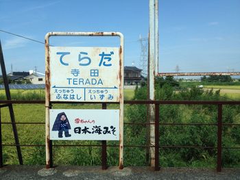 Non-western script on sign board by railing against sky