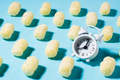 A trending background of corn sticks and an alarm clock on a blue backdrop in hard light