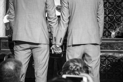 Rear view of gay couple holding hands during wedding ceremony in church