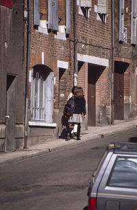 Rear view of man on street against buildings in city