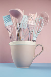 Close-up of utensils in tea cup on table against wall