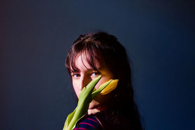 Portrait of woman holding flower against blue background