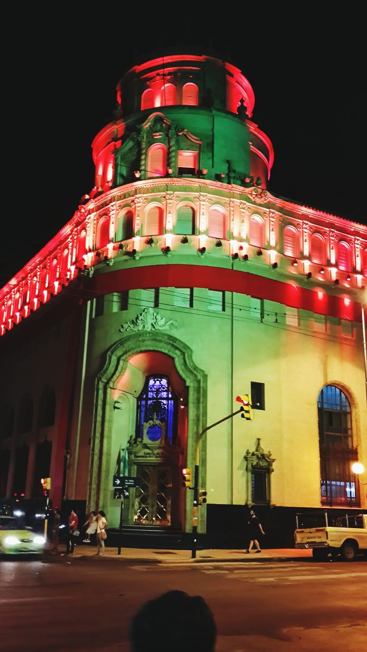 architecture, building exterior, built structure, illuminated, night, street, transportation, low angle view, place of worship, religion, clear sky, road, car, church, facade, city, land vehicle, arch, travel, incidental people