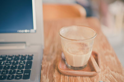 Close-up of coffee in glass with laptop on table
