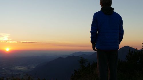 Man standing on mountain against sky during sunset