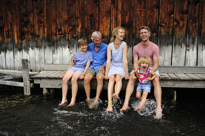 Family sitting together on jetty splashing with water