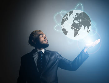 Digital composite image of businessman holding globe against colored background