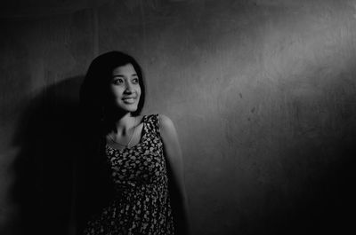 Beautiful young woman standing against wall