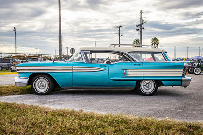 Vintage car on street in city against sky