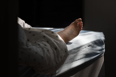 Low section of person relaxing on bed