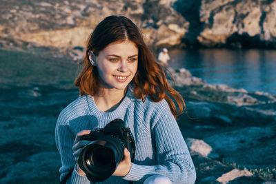 Portrait of smiling young woman holding camera