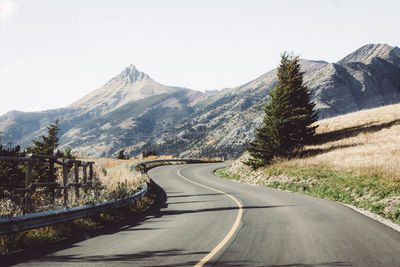 Road leading towards mountains against clear sky