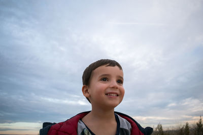 Low angle view of young woman standing against sky