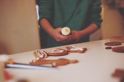 Midsection of girl decorating gingerbread cookies on table