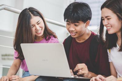 Friends looking away while sitting on laptop