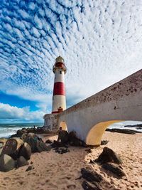 Lighthouse by sea against sky