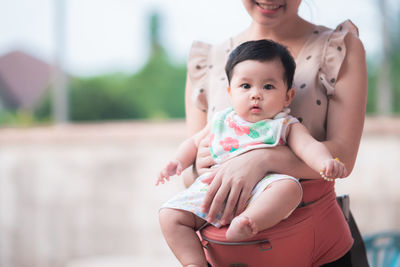 Midsection mother carrying daughter while standing outdoors