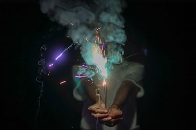 Person holding lit sparklers at night