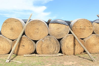 Stack of hay bales on field against sky