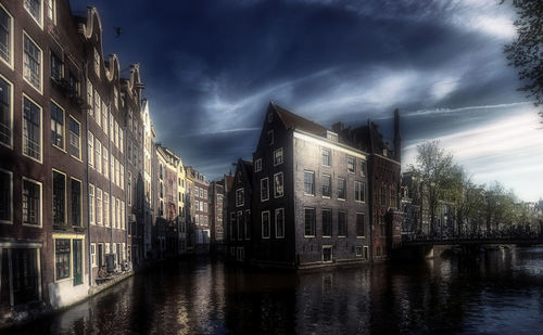 Canal amidst buildings against sky at dusk