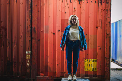 Portrait of woman standing against cargo container