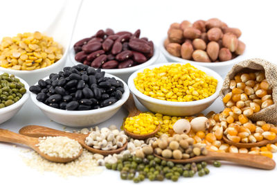 A variety of grains, such as black beans, red beans, dehydrated corn on white background.