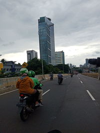 Rear view of people riding bicycle on road