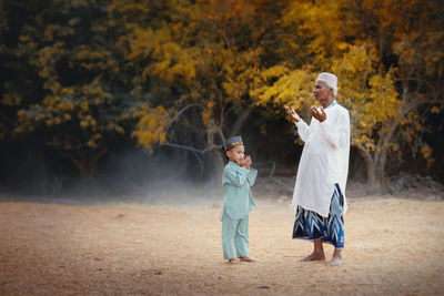 Grandfather and grandson gesturing while standing outdoors