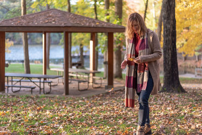 Full length of woman holding autumn tree