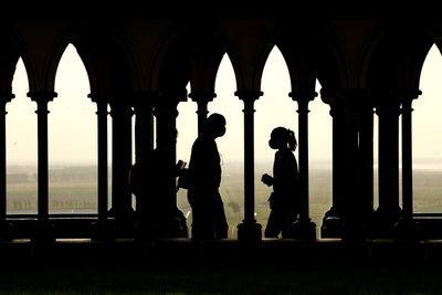 Silhouette people walking by building