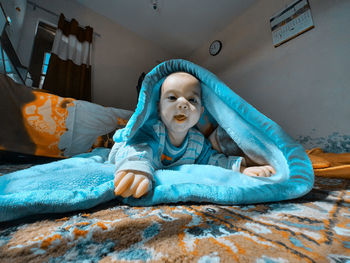 Portrait of cute boy lying on bed at home