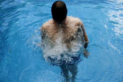 High angle view of shirtless man swimming in pool