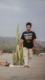 Portrait of smiling man standing by plant against sky