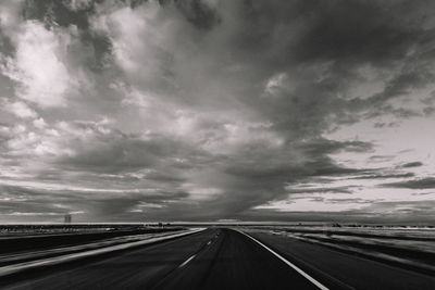 Country road against cloudy sky