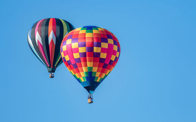 Hot air balloons float in a clear blue sky on a sunny day