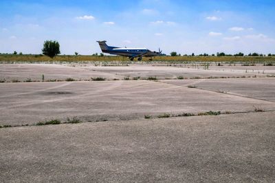 Airplane on airport runway against sky