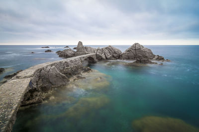 Scenic view of rocks in sea against sky