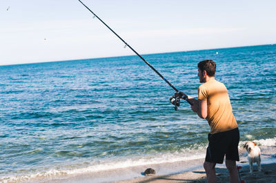 Rear view of man fishing on beach