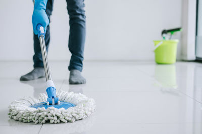 Low section of person cleaning tied floor at home