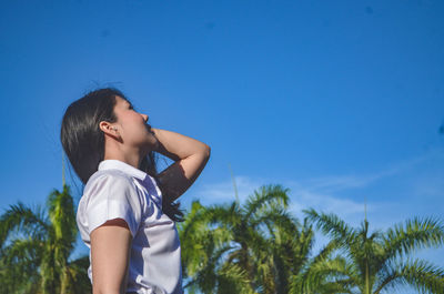 Low angle view of woman standing against blue sky