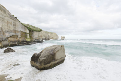 Scenic view of rocks on beach against sky